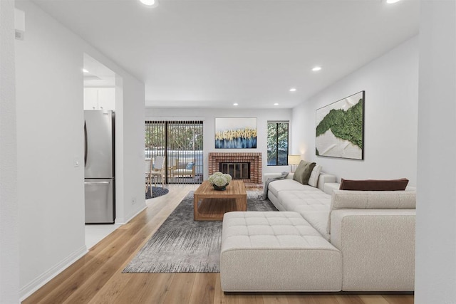 living area with recessed lighting, baseboards, light wood-style flooring, and a fireplace