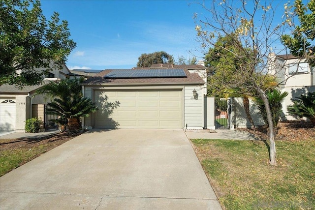 single story home with a garage, a front lawn, and solar panels