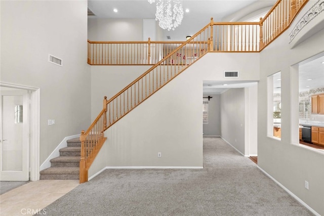 stairway featuring a towering ceiling, carpet, visible vents, and baseboards