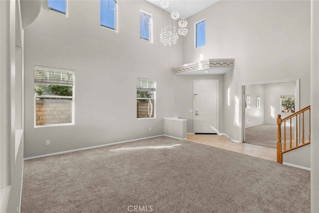 unfurnished living room featuring baseboards, carpet floors, stairway, and a notable chandelier