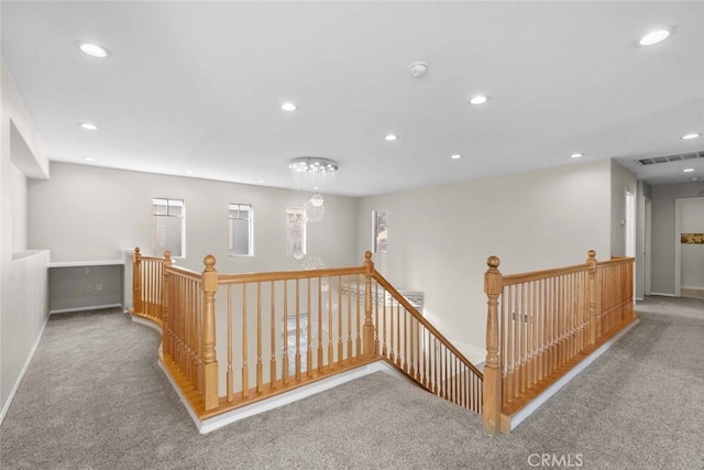 hall featuring a chandelier, recessed lighting, carpet floors, and an upstairs landing