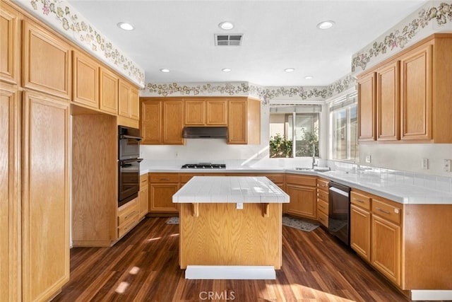 kitchen featuring dark wood finished floors, tile countertops, a kitchen island, appliances with stainless steel finishes, and under cabinet range hood