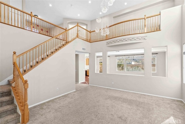 unfurnished living room with a high ceiling, carpet floors, and an inviting chandelier