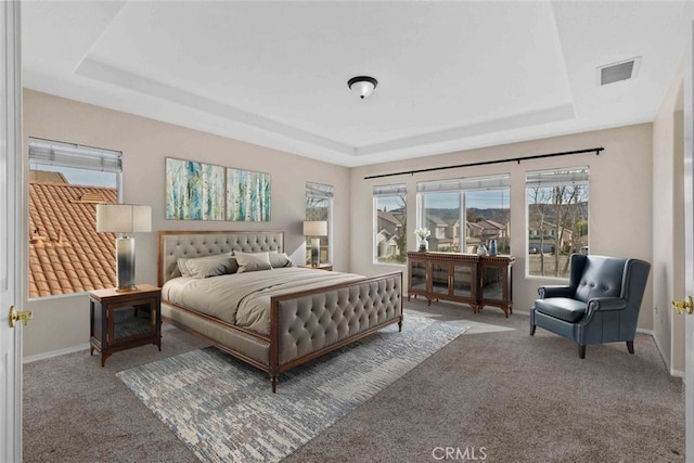 bedroom featuring carpet, a raised ceiling, visible vents, and baseboards