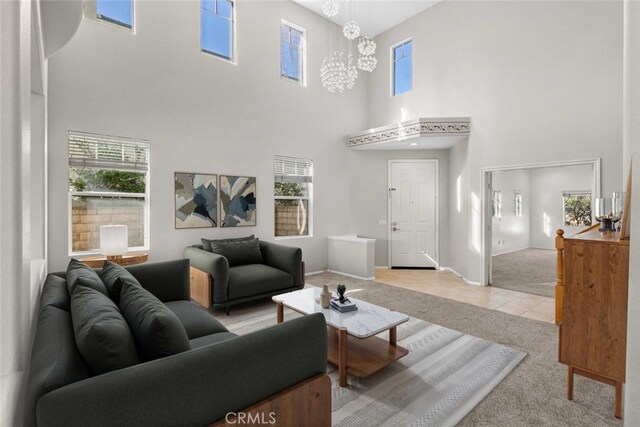 living room featuring a towering ceiling, a chandelier, and light carpet