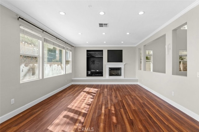 unfurnished living room featuring visible vents, crown molding, baseboards, and wood finished floors