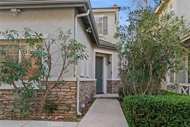 doorway to property with stone siding and stucco siding