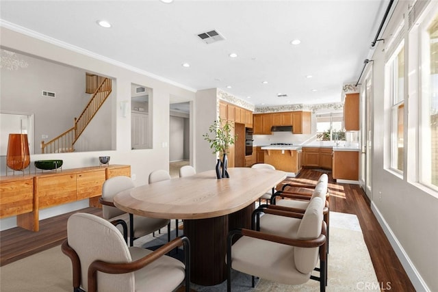 dining space featuring dark wood-type flooring and crown molding