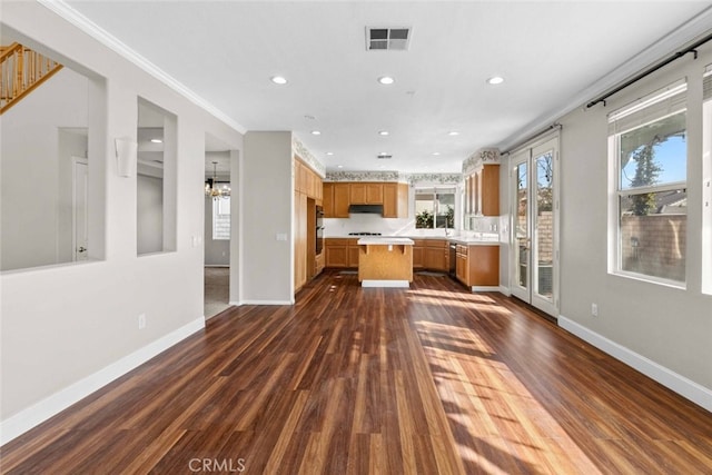 kitchen featuring dark hardwood / wood-style flooring, ornamental molding, a center island, and an inviting chandelier