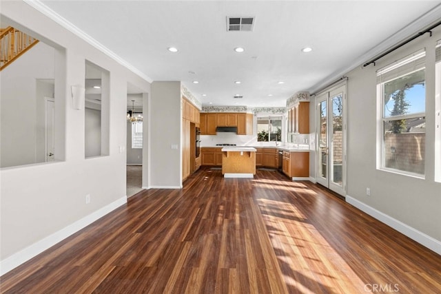 kitchen with visible vents, baseboards, light countertops, dark wood-style floors, and brown cabinetry