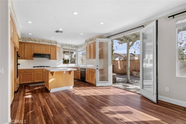 kitchen featuring a breakfast bar area, gas cooktop, dark hardwood / wood-style flooring, dishwasher, and a kitchen island