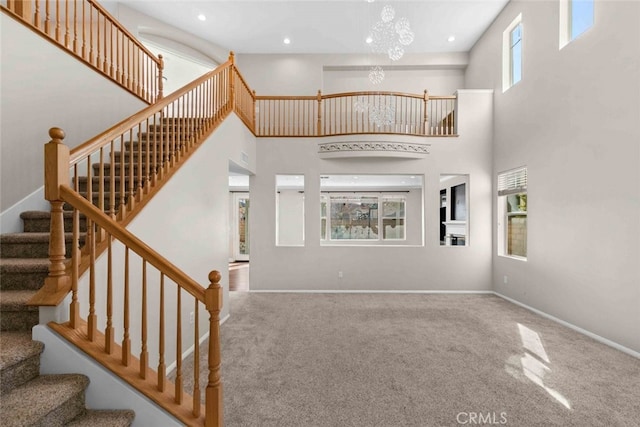 stairs featuring a towering ceiling, a chandelier, and carpet