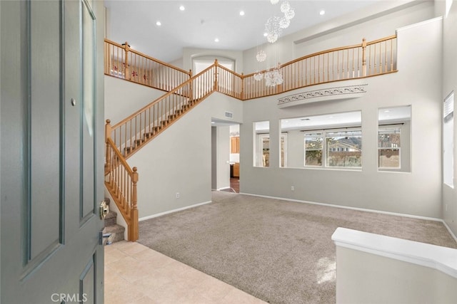 carpeted foyer entrance with recessed lighting, a high ceiling, baseboards, stairs, and an inviting chandelier