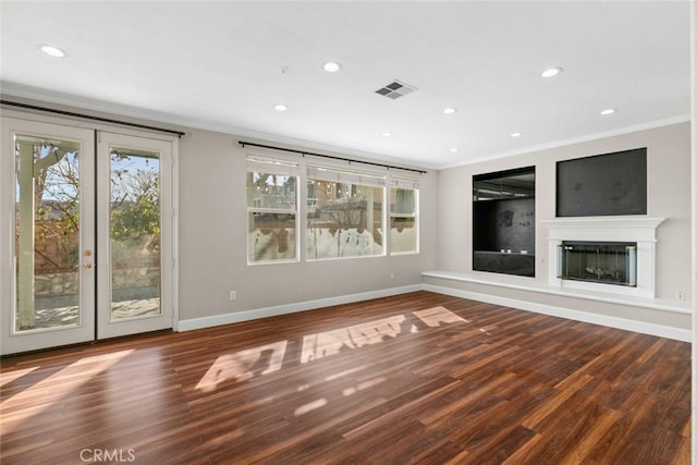 unfurnished living room with ornamental molding, a glass covered fireplace, visible vents, and a healthy amount of sunlight