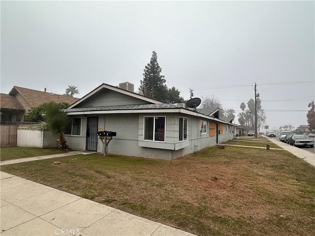 view of front of home with cooling unit and a front yard