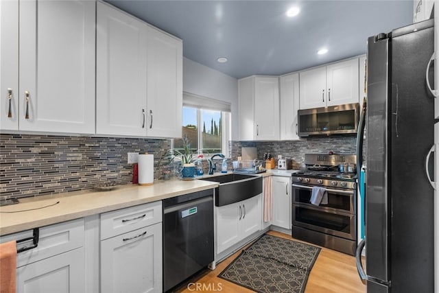 kitchen with tasteful backsplash, sink, white cabinets, and appliances with stainless steel finishes