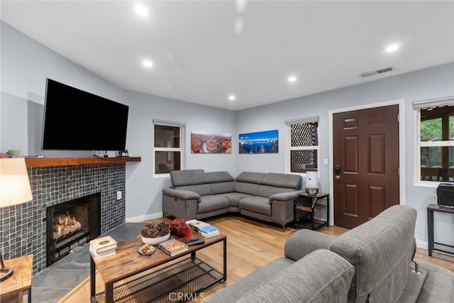 living room featuring a tile fireplace and light wood-type flooring