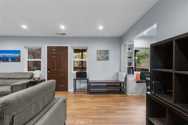 living room featuring built in shelves and light hardwood / wood-style floors