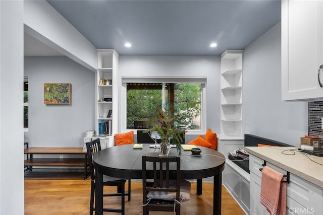 dining room featuring built in shelves and light wood-type flooring