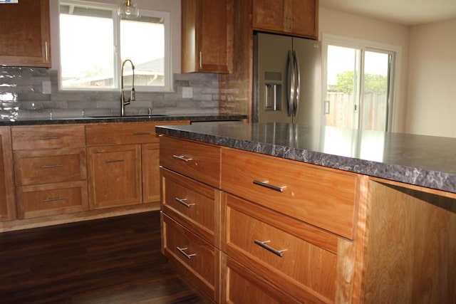 kitchen with stainless steel fridge with ice dispenser, dark hardwood / wood-style floors, sink, and backsplash