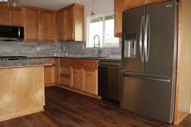 kitchen with sink, appliances with stainless steel finishes, hanging light fixtures, dark hardwood / wood-style floors, and tasteful backsplash