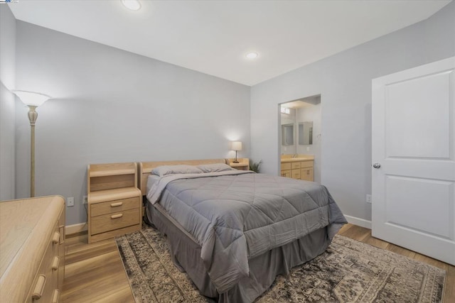 bedroom featuring ensuite bathroom, sink, and light hardwood / wood-style flooring