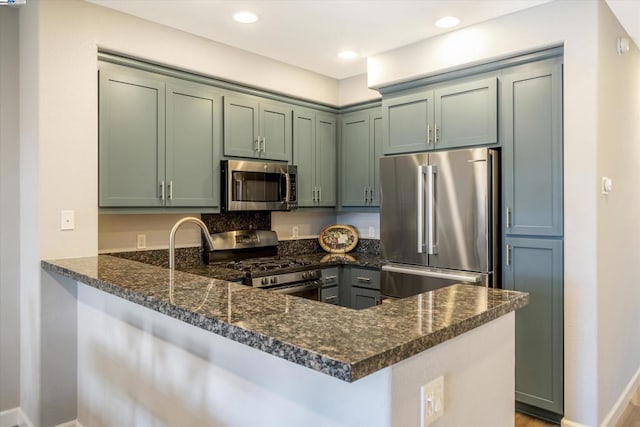 kitchen featuring green cabinetry, appliances with stainless steel finishes, dark stone countertops, and kitchen peninsula