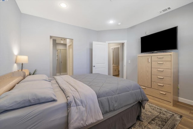 bedroom with light hardwood / wood-style flooring and ensuite bathroom