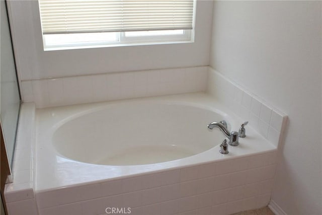 bathroom with tiled tub and a healthy amount of sunlight