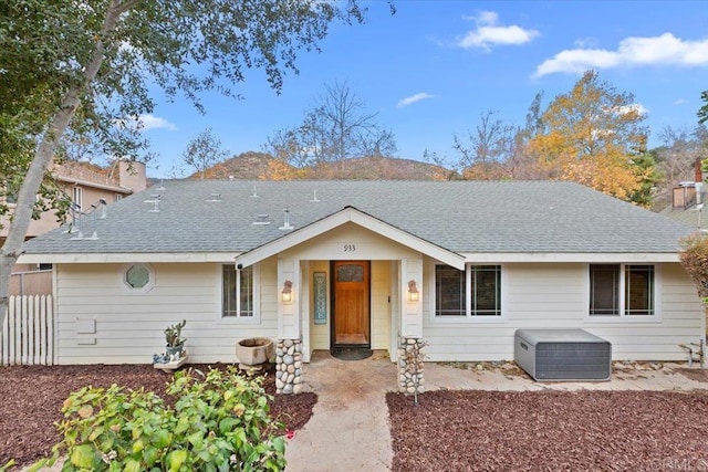 ranch-style house with a chimney, roof with shingles, and fence