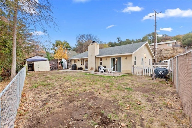 rear view of property with a shed, a patio, an outdoor structure, and a fenced backyard