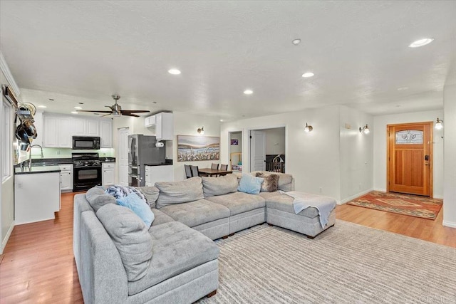 living room with recessed lighting, baseboards, and light wood finished floors