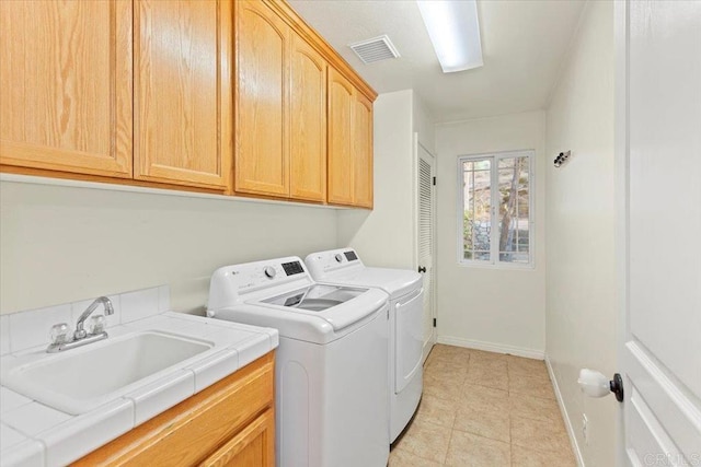 washroom with visible vents, a sink, cabinet space, separate washer and dryer, and baseboards