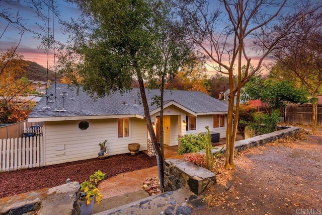 view of front of house featuring roof with shingles and fence