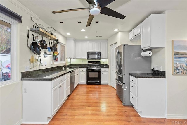 kitchen with light wood-style flooring, recessed lighting, a sink, black appliances, and white cabinetry