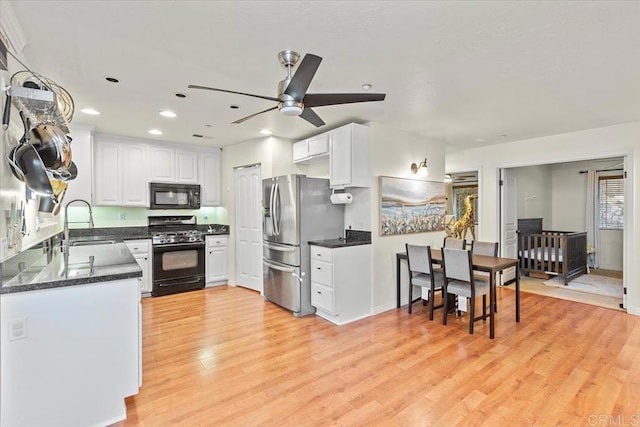 kitchen featuring a sink, light wood-style floors, black appliances, and white cabinets