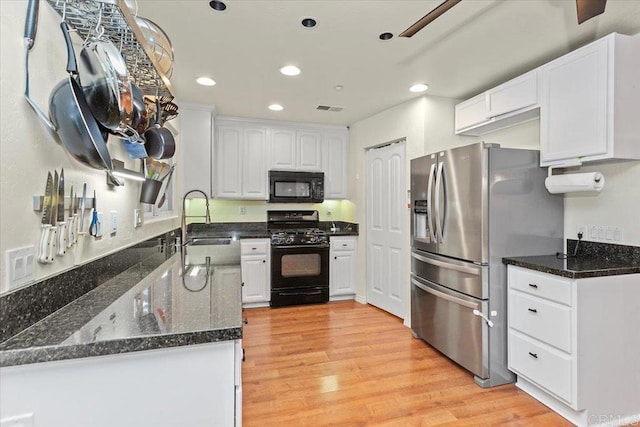 kitchen with visible vents, black appliances, a sink, white cabinets, and light wood finished floors