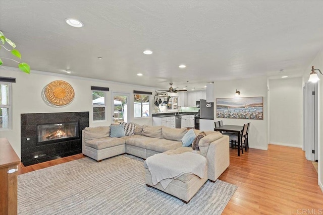 living room featuring a wealth of natural light, recessed lighting, light wood finished floors, and a premium fireplace