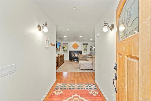 foyer featuring a glass covered fireplace, baseboards, and light wood finished floors