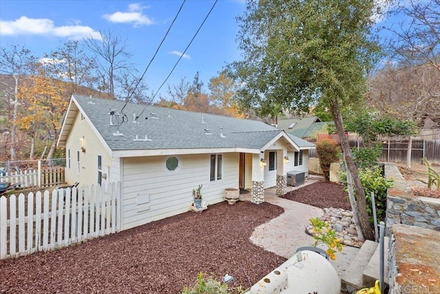 view of front of property with cooling unit, a fenced backyard, and a shingled roof