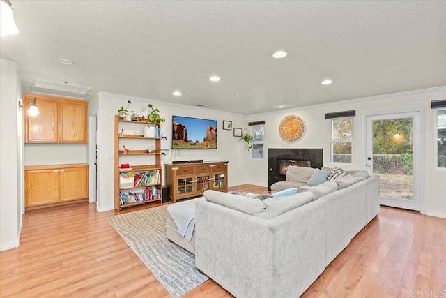 living area with a high end fireplace, recessed lighting, light wood-style floors, and ornamental molding