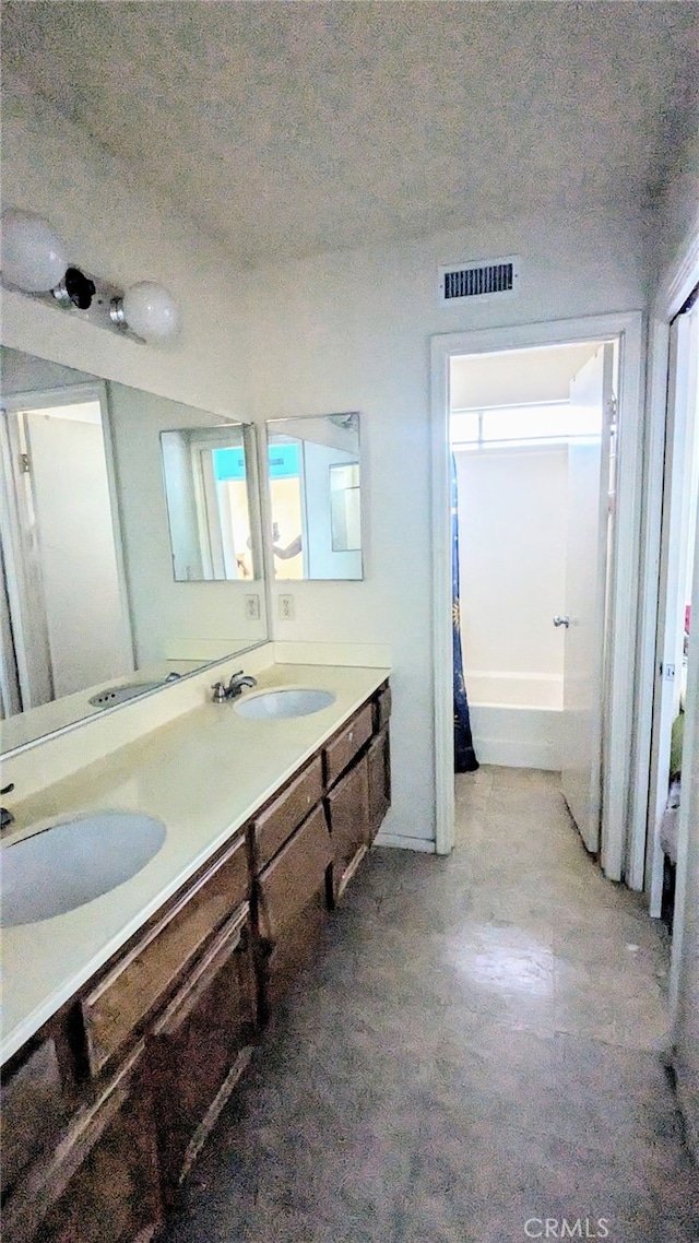 bathroom with vanity, a bathing tub, and a textured ceiling