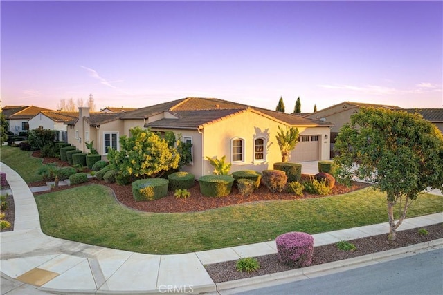 mediterranean / spanish-style home featuring a garage and a lawn