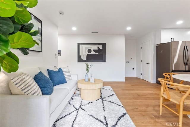 living area with light wood finished floors, visible vents, recessed lighting, and baseboards