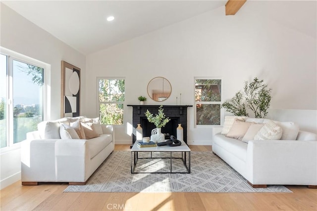 living area featuring beamed ceiling, a brick fireplace, baseboards, and wood finished floors