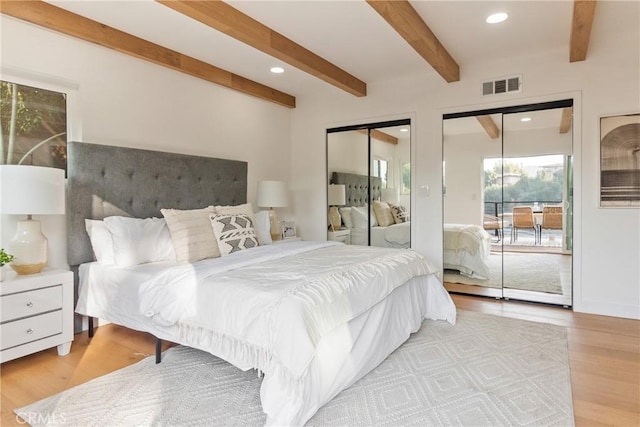 bedroom with wood finished floors, visible vents, recessed lighting, beamed ceiling, and two closets