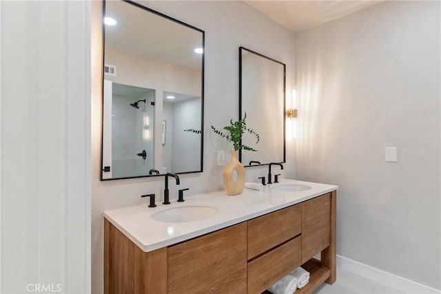 full bath featuring double vanity, baseboards, and a sink