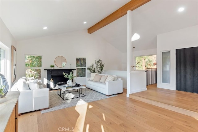 living room with beamed ceiling, plenty of natural light, and wood finished floors