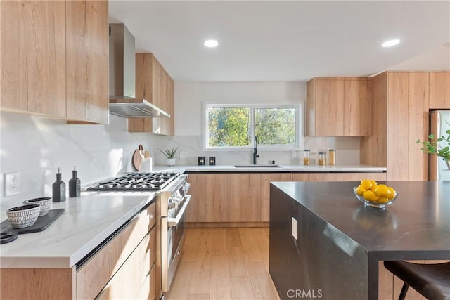 kitchen featuring a sink, wall chimney range hood, stainless steel stove, and modern cabinets