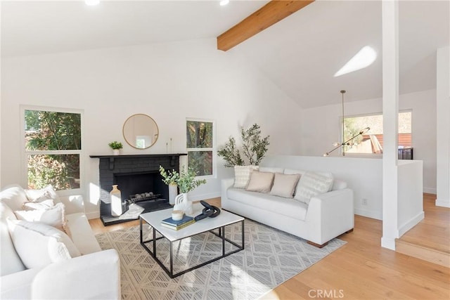 living area featuring baseboards, beam ceiling, a fireplace, wood finished floors, and high vaulted ceiling